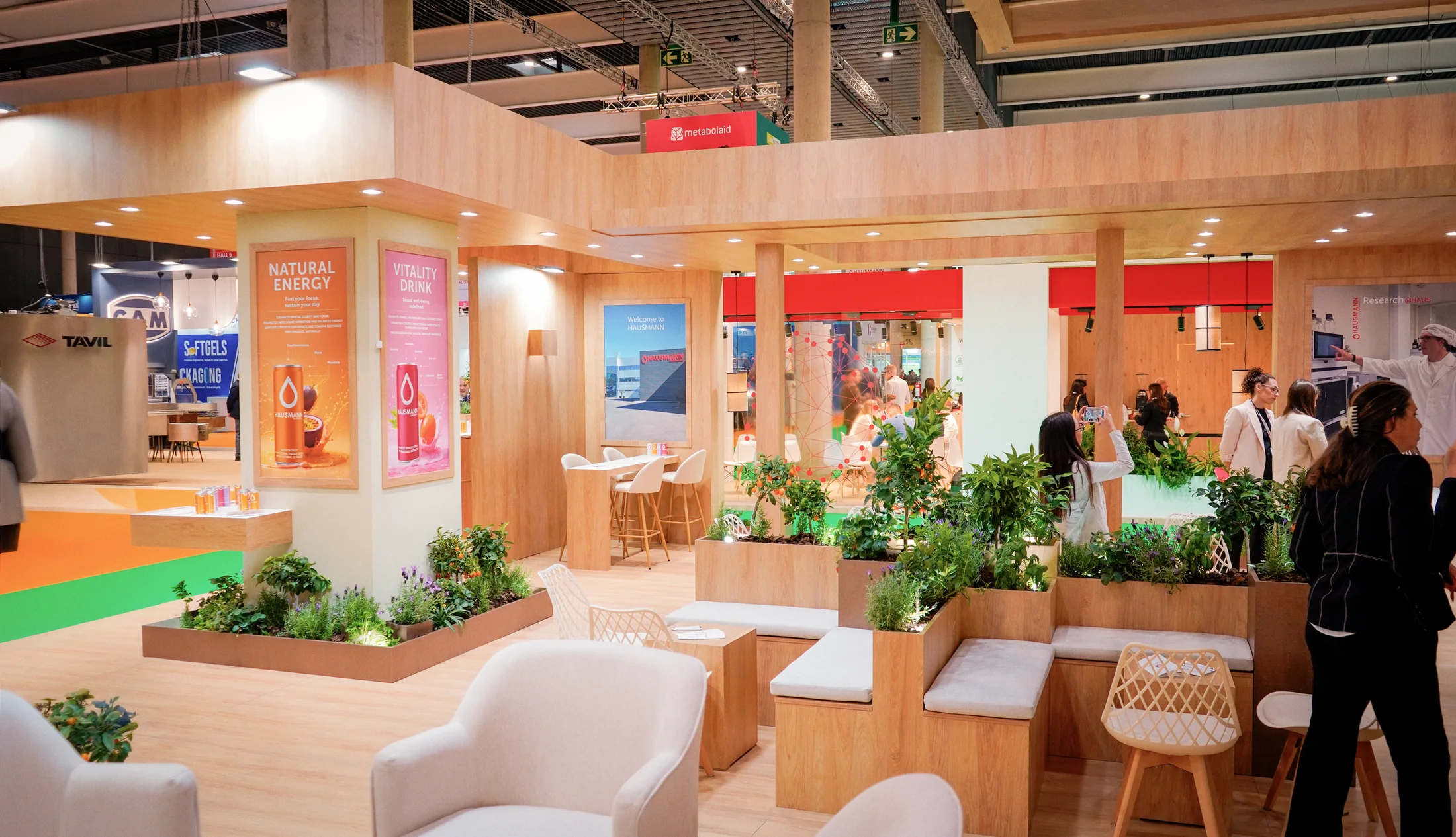 Zona lounge de madera con vegetación en un stand diseñado por ROCMA